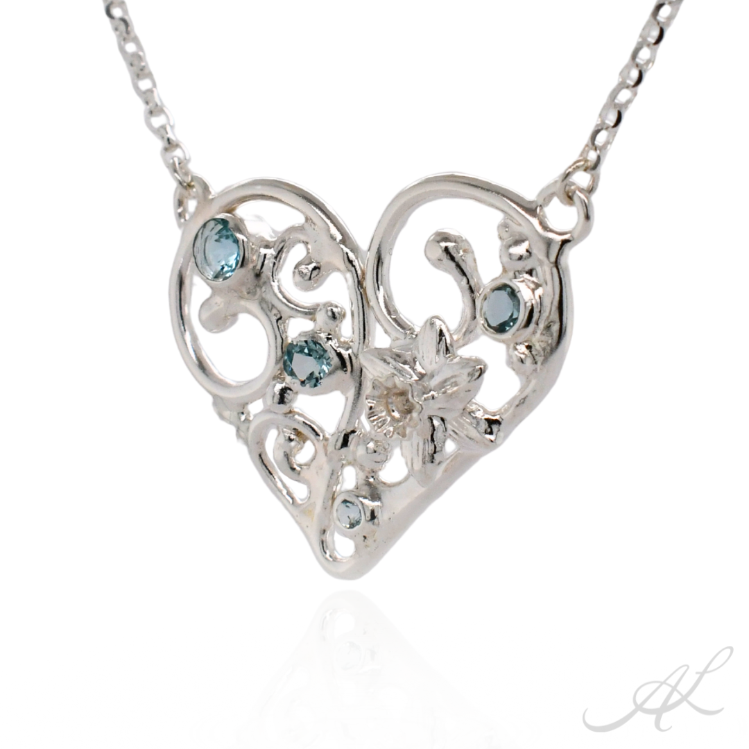 Silver heart-shaped necklace with blue gemstones on a white background